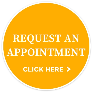 Circular yellow button displaying the text “REQUEST AN APPOINTMENT” and “CLICK HERE” with a right-arrow symbol.