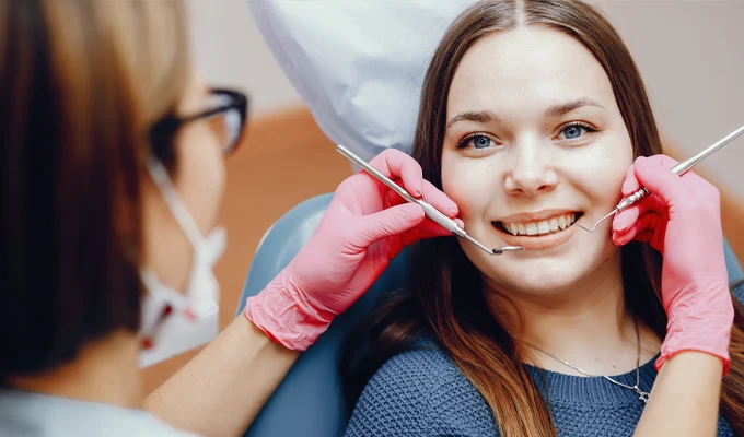 Dental professional using examination tools while a patient sits in a treatment chair during a consultation.